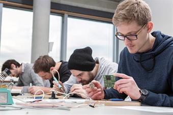 Dieses Bild zeigt eine Gruppe männliche Studierende beim arbeiten.